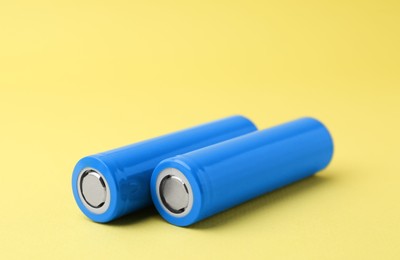 Photo of Two AA cell batteries on yellow background, closeup. Space for text