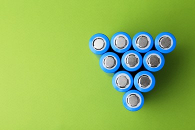 Photo of Many AA cell batteries on green background, top view. Space for text