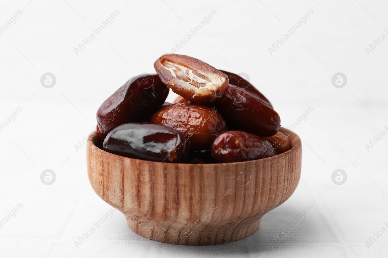 Photo of Tasty dried dates in bowl on white table, closeup