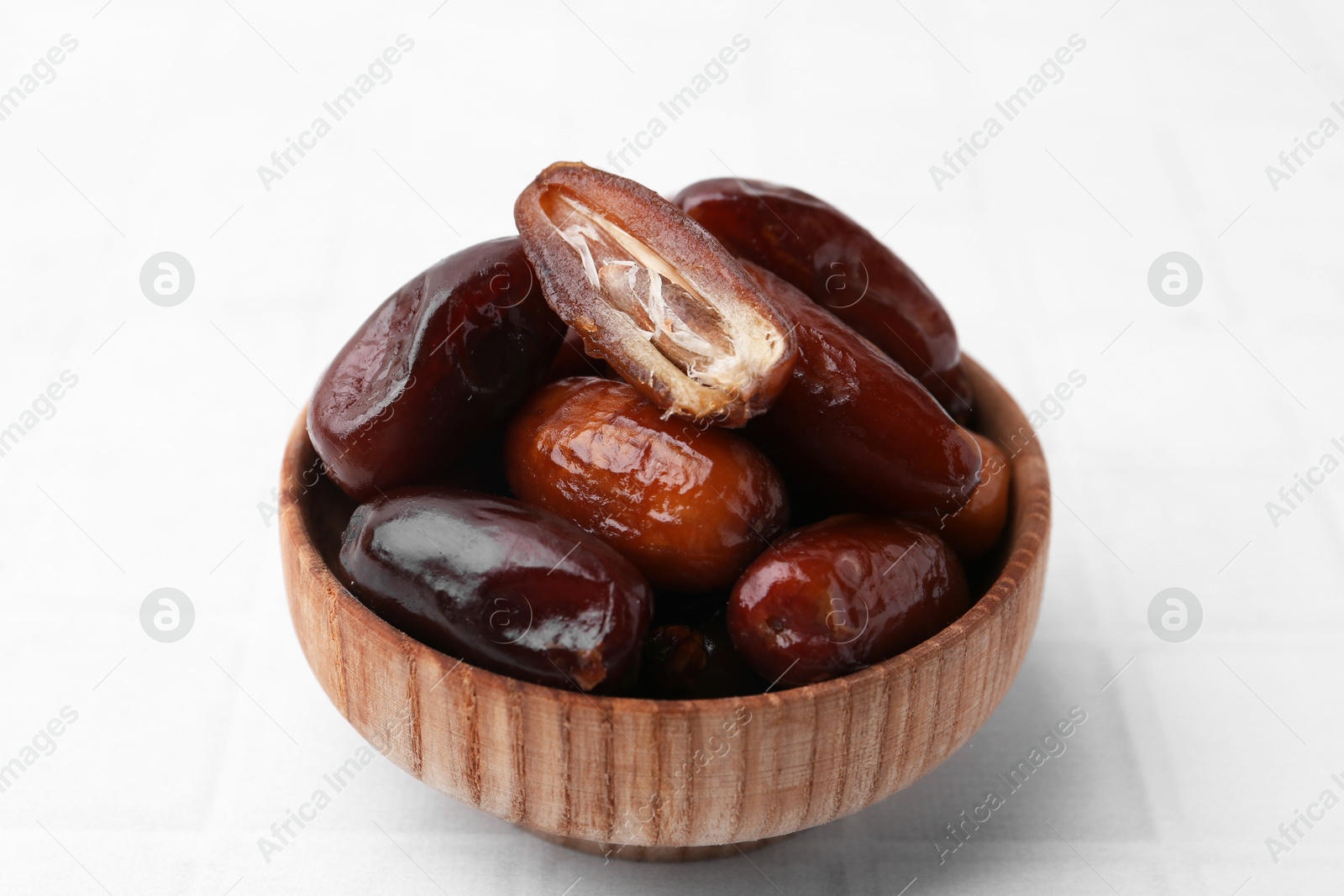 Photo of Tasty dried dates in bowl on white table, closeup