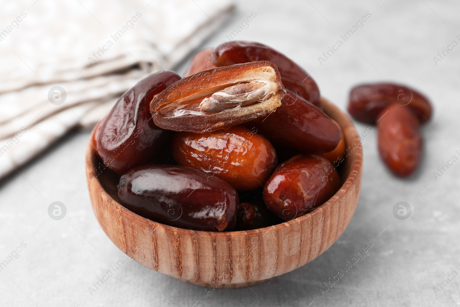 Photo of Tasty dried dates in bowl on light grey table, closeup