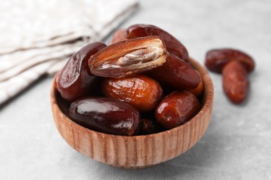 Photo of Tasty dried dates in bowl on light grey table, closeup