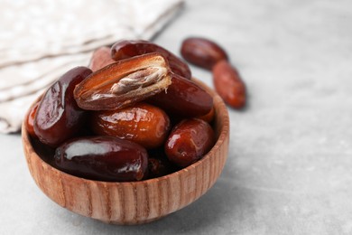 Photo of Tasty dried dates in bowl on light grey table, closeup. Space for text