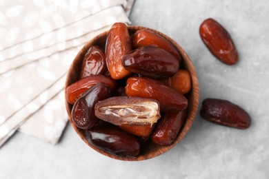 Photo of Tasty dried dates in bowl on light grey table, top view