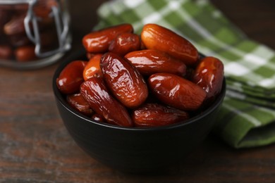 Photo of Tasty dried dates in bowl on wooden table, closeup