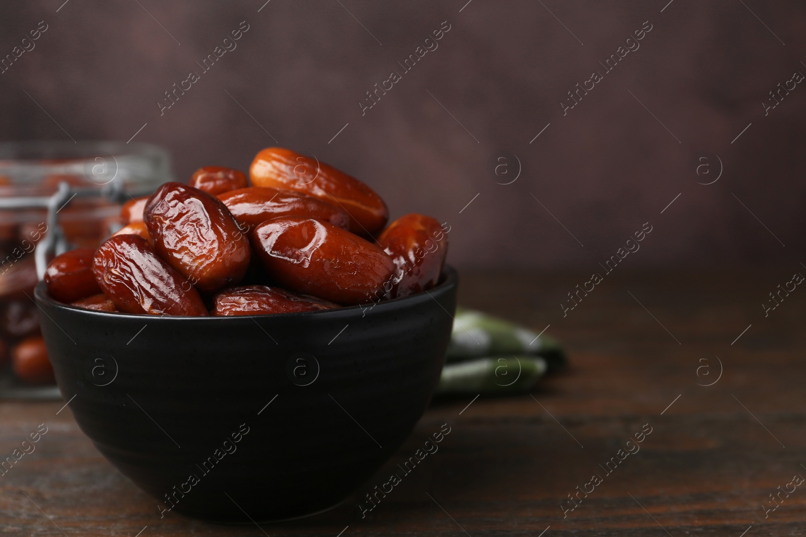 Photo of Tasty dried dates in bowl on wooden table, closeup. Space for text