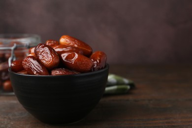 Photo of Tasty dried dates in bowl on wooden table, closeup. Space for text