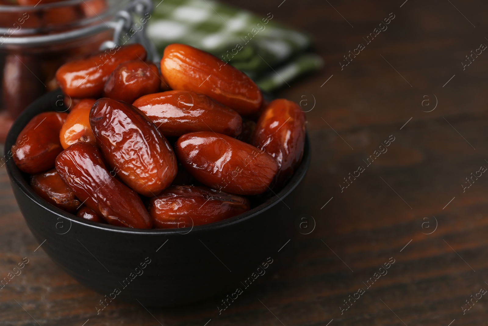 Photo of Tasty dried dates in bowl on wooden table, closeup. Space for text