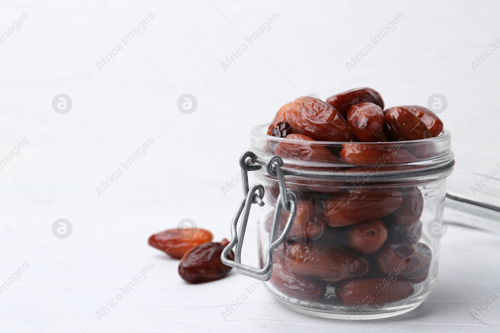 Photo of Tasty dried dates in jar on white table, closeup. Space for text