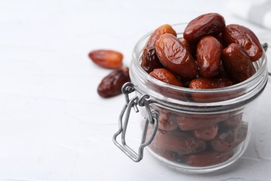 Photo of Tasty dried dates in jar on white table, closeup. Space for text