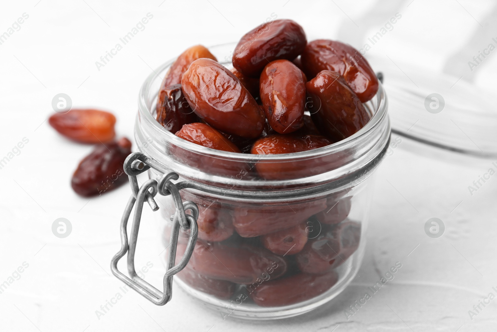 Photo of Tasty dried dates in jar on white table, closeup