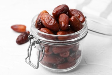 Photo of Tasty dried dates in jar on white table, closeup