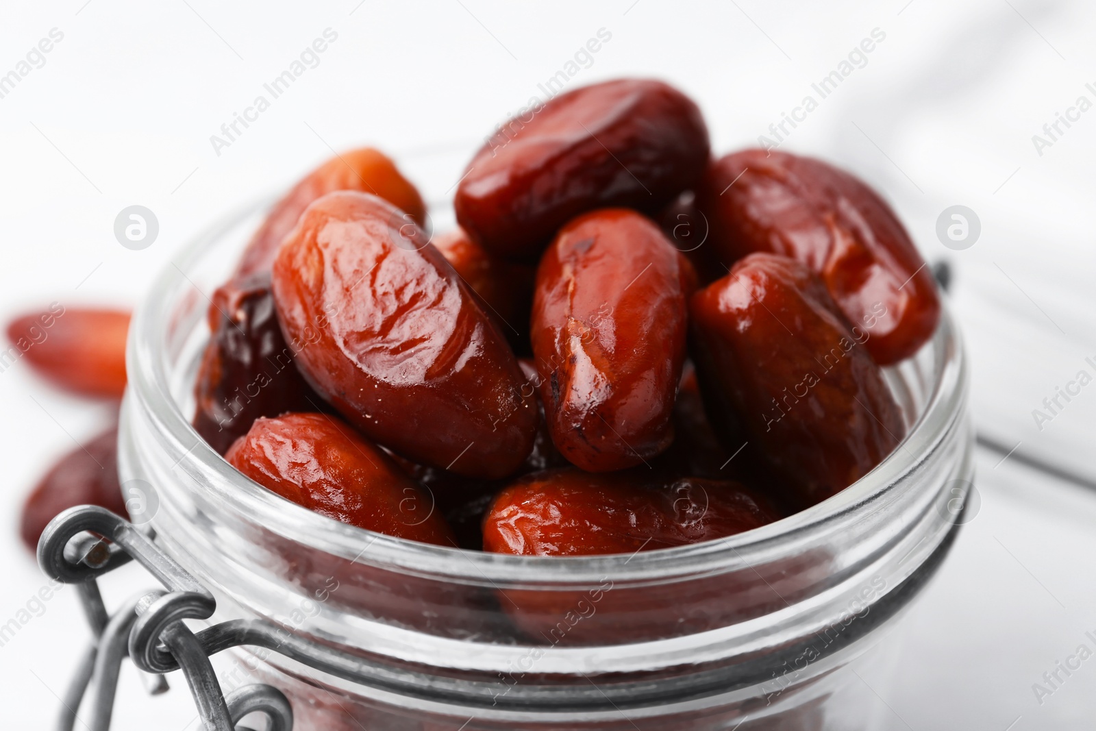 Photo of Tasty dried dates in jar on white table, closeup