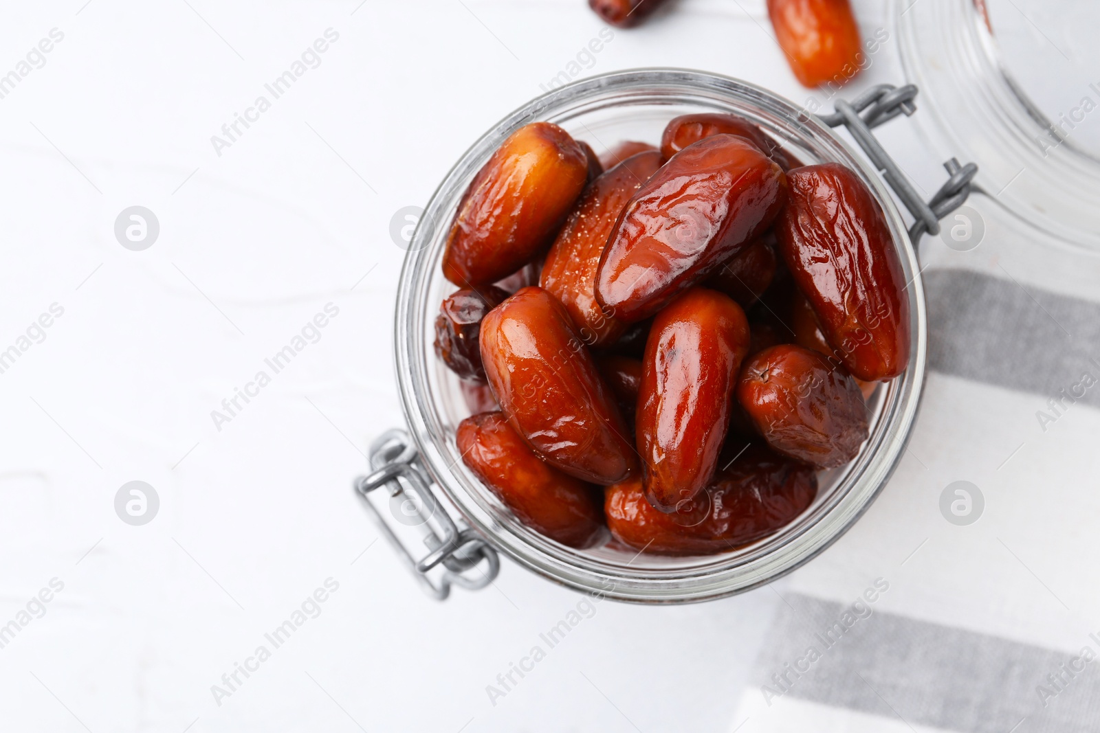 Photo of Tasty dried dates in jar on white table, top view. Space for text