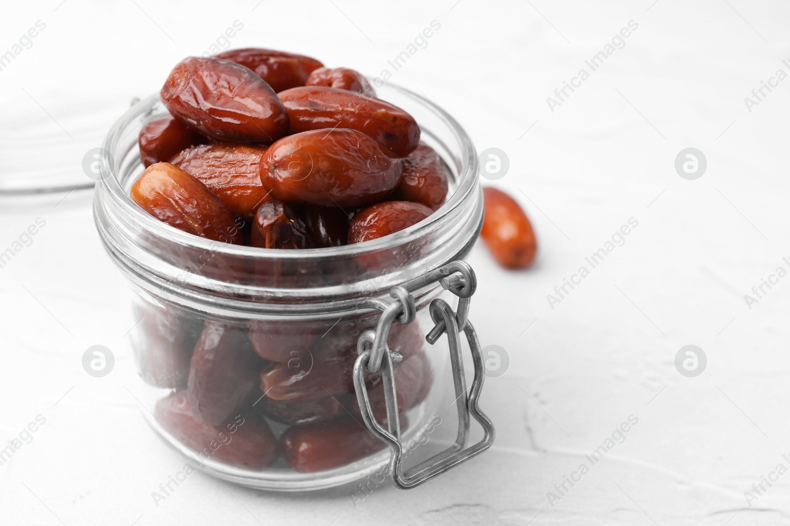 Photo of Tasty dried dates in jar on white table, closeup. Space for text