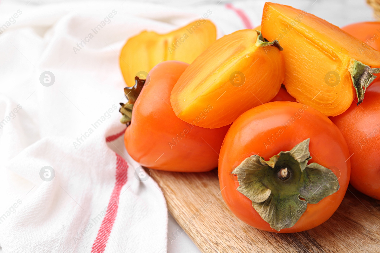 Photo of Whole and cut ripe persimmons on table, closeup