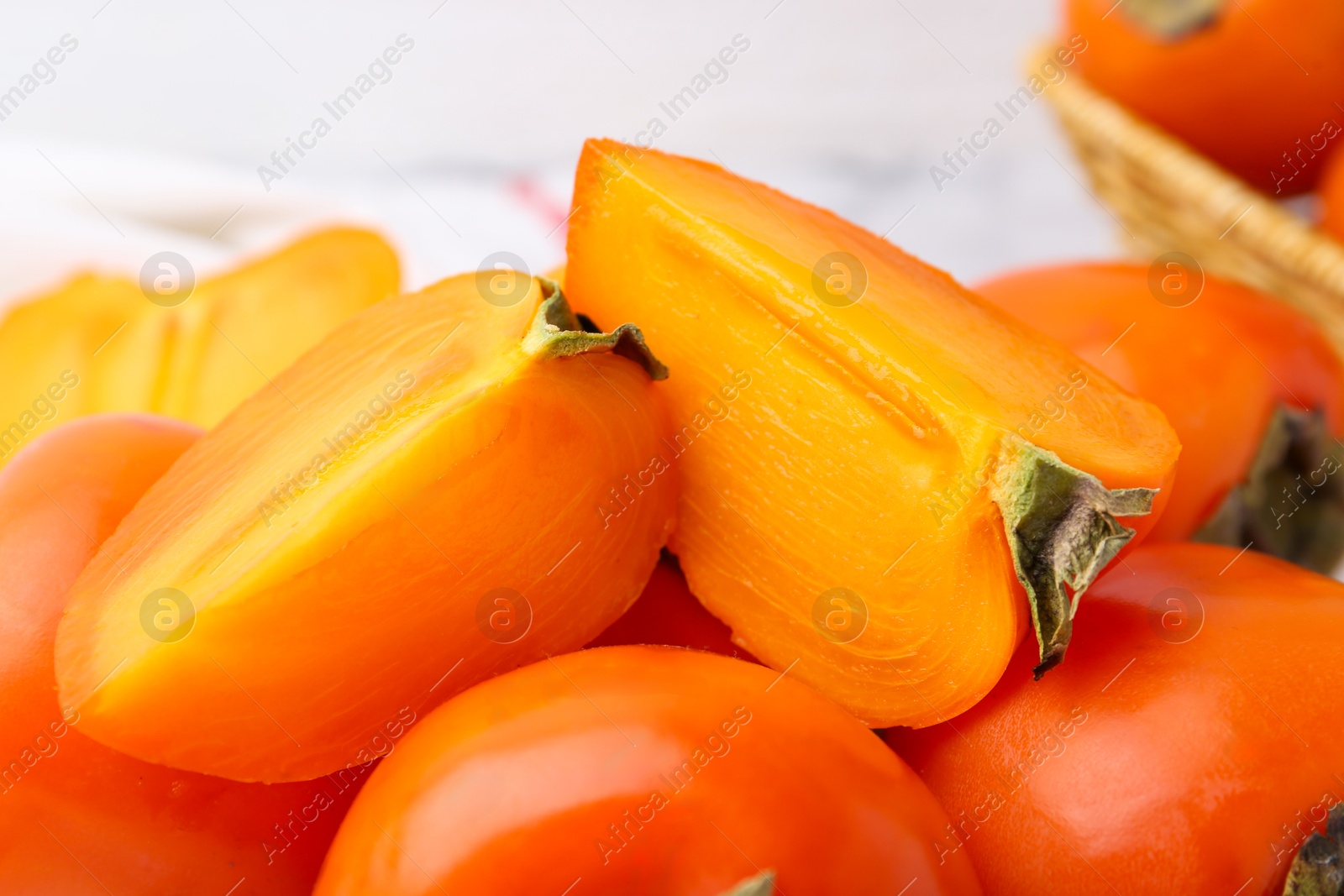 Photo of Whole and cut ripe persimmons on table, closeup