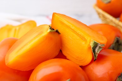 Whole and cut ripe persimmons on table, closeup