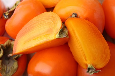 Photo of Whole and cut ripe persimmons as background, closeup