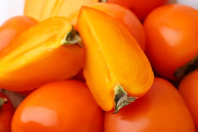 Photo of Whole and cut ripe persimmons as background, closeup