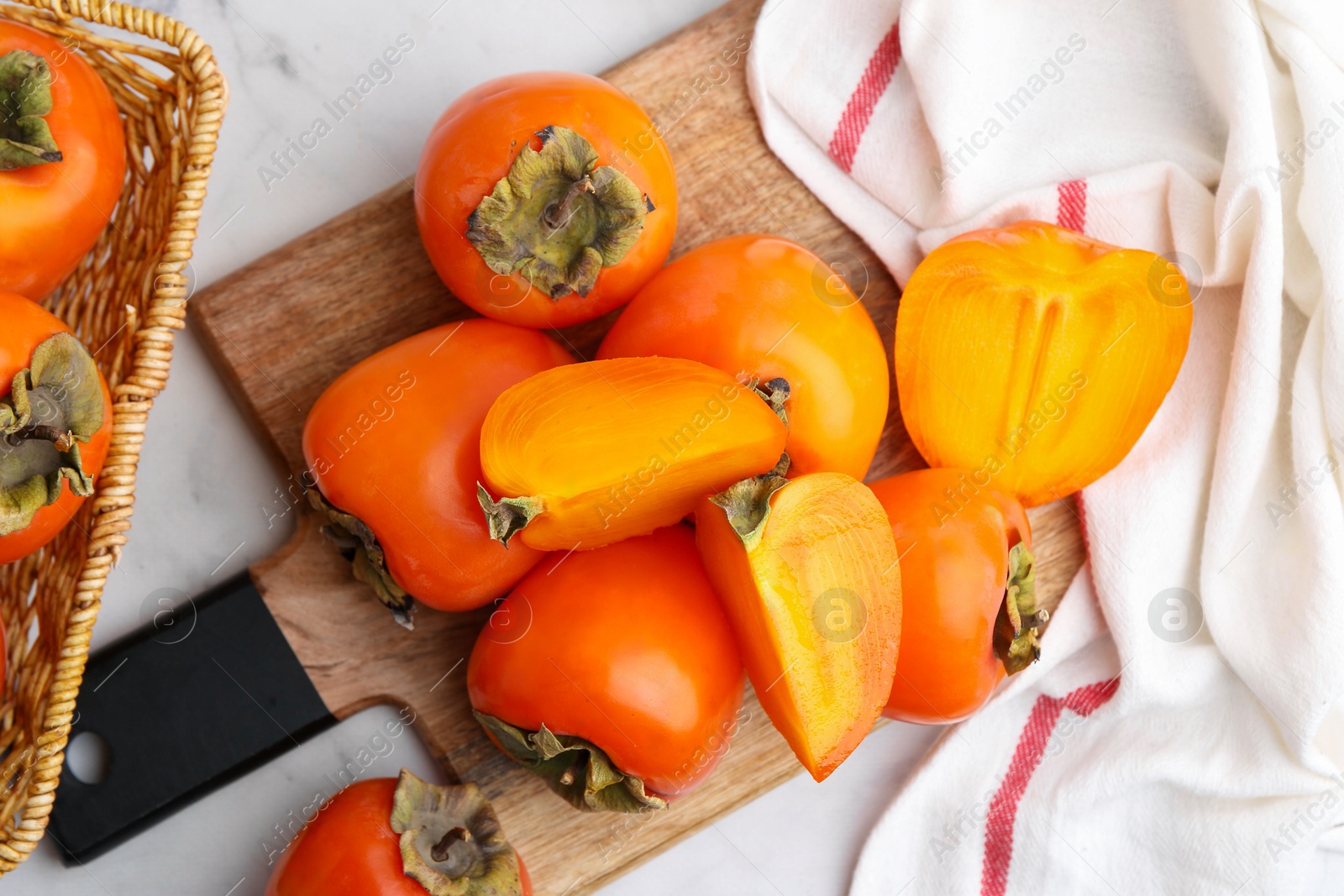 Photo of Whole and cut ripe persimmons on white table, flat lay