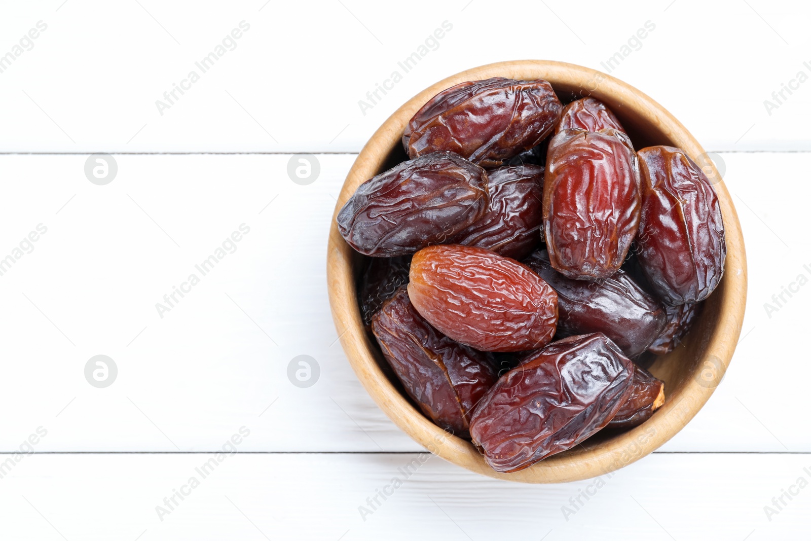 Photo of Tasty dried dates on white wooden table, top view. Space for text