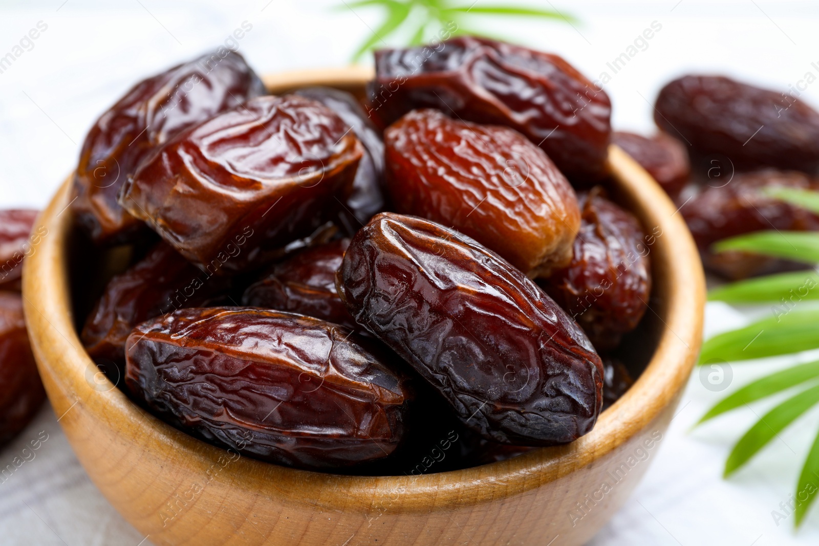 Photo of Tasty dried dates and leaves on white table, closeup