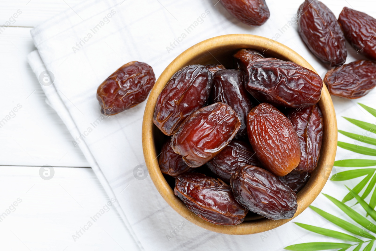 Photo of Tasty dried dates and leaves on white wooden table, flat lay