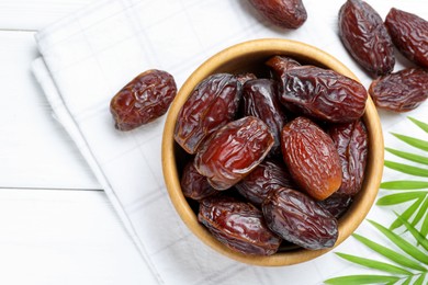 Photo of Tasty dried dates and leaves on white wooden table, flat lay