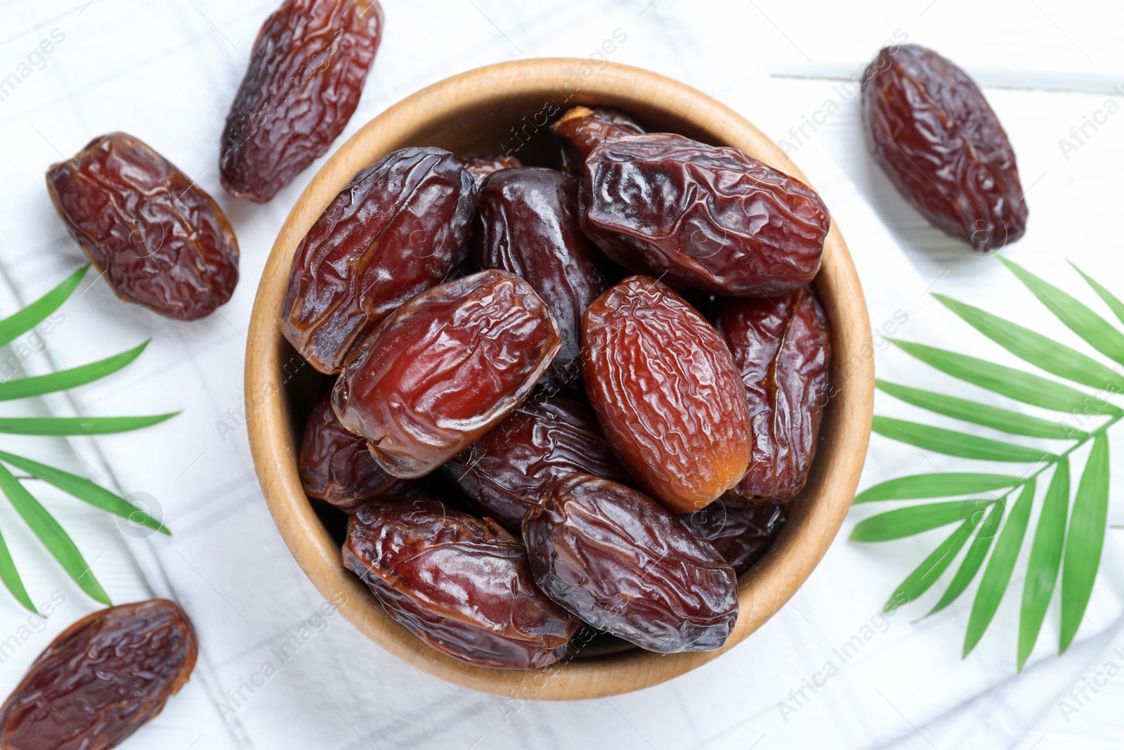 Photo of Tasty dried dates and leaves on white table, flat lay