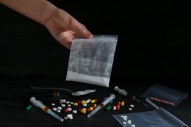 Photo of Drug addiction. Woman holding plastic bag with powder against dark background, closeup