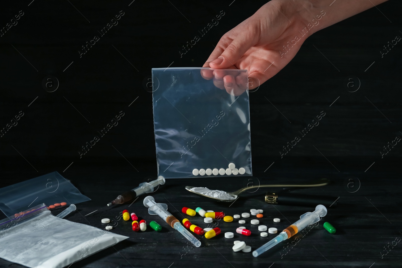 Photo of Drug addiction. Woman holding plastic bag with pills against dark background, closeup