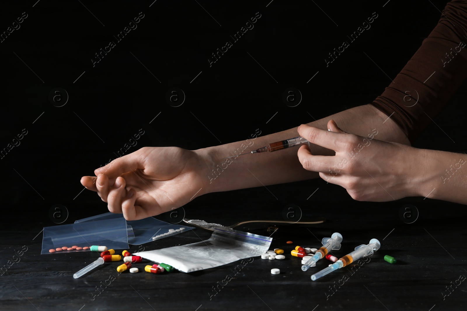 Photo of Drug addiction. Woman with syringe against dark background, closeup