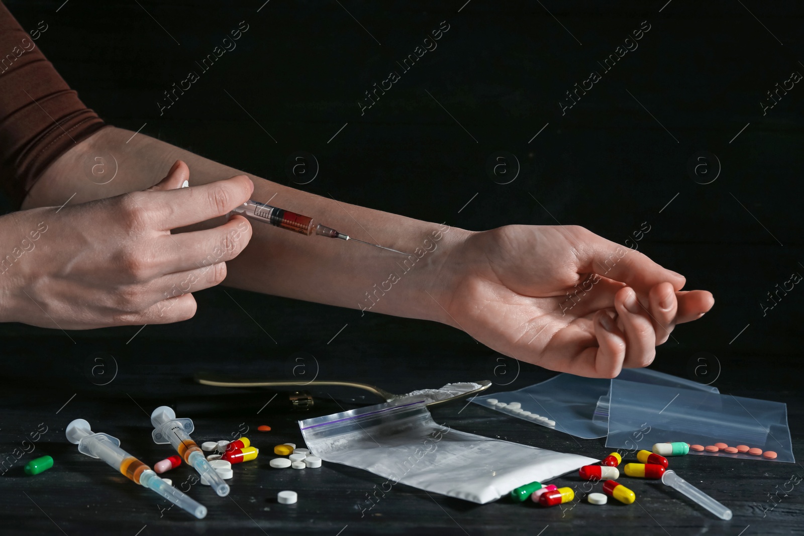 Photo of Drug addiction. Woman with syringe against dark background, closeup