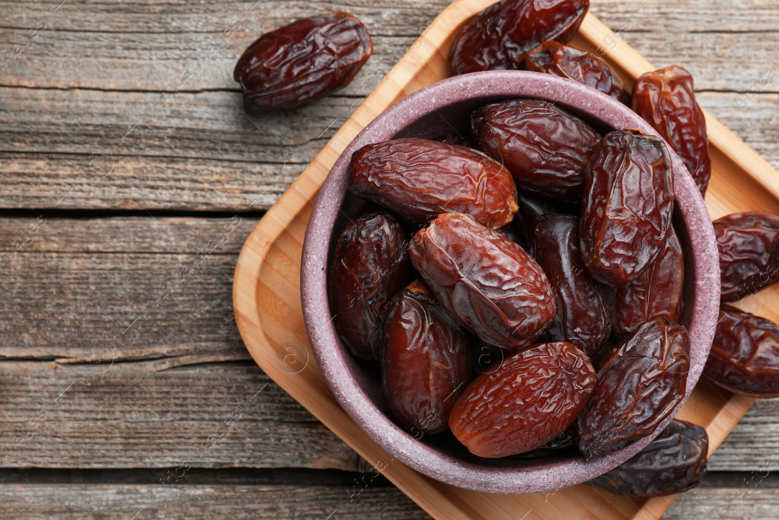 Photo of Many tasty dried dates in bowl on table, top view. Space for text