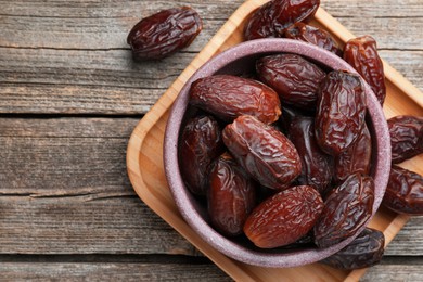 Photo of Many tasty dried dates in bowl on table, top view. Space for text