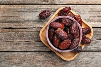 Photo of Many tasty dried dates in bowl on table, top view. Space for text