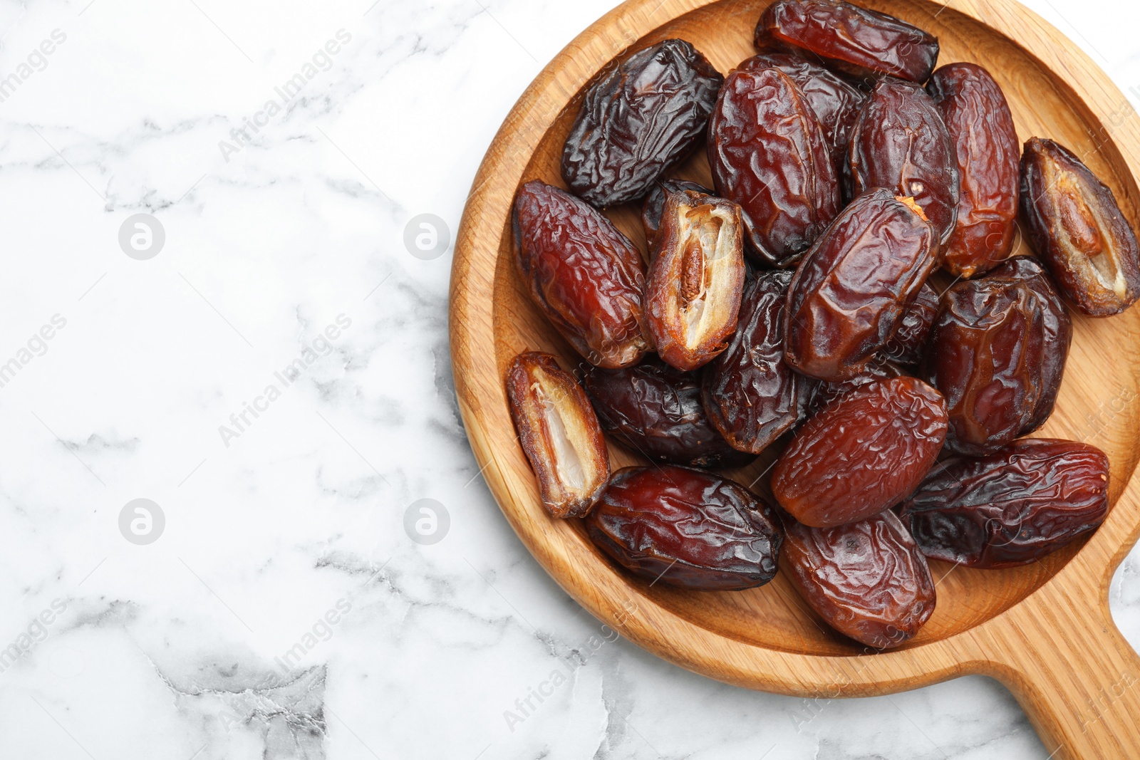 Photo of Many tasty dried dates on white marble table, top view. Space for text