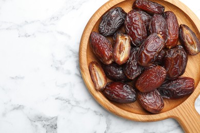 Photo of Many tasty dried dates on white marble table, top view. Space for text