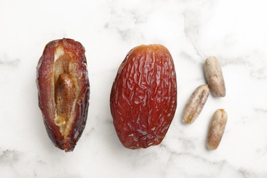 Photo of Tasty dried dates with seeds on white marble table, flat lay