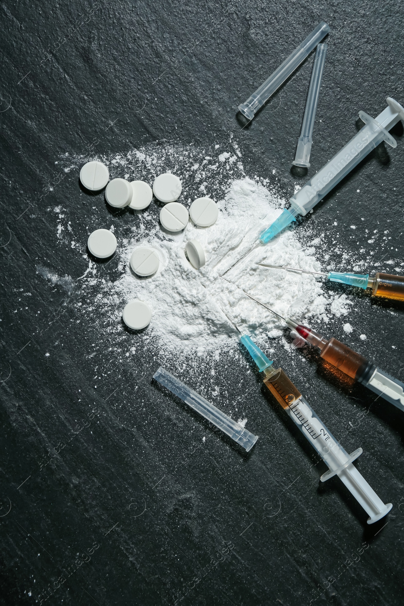 Photo of Drug addiction. Powder, pills and syringes on black textured table, flat lay