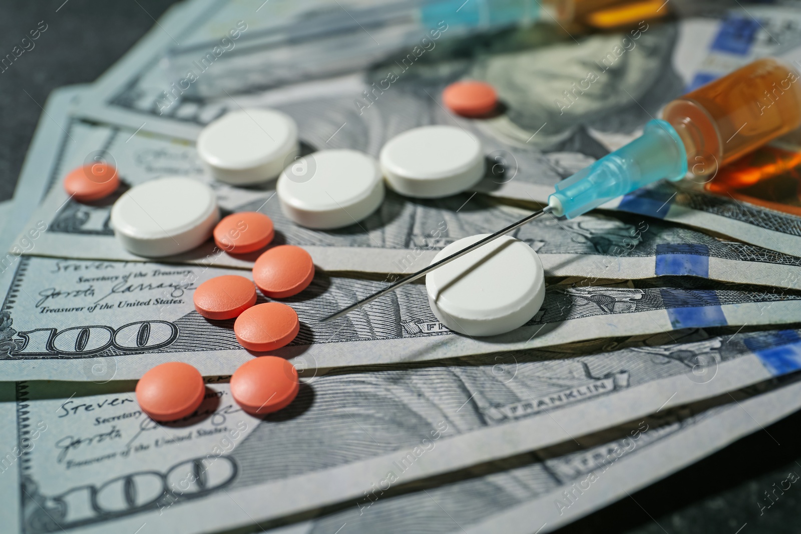 Photo of Drug addiction. Dollar banknotes, pills and syringe on gray table, closeup