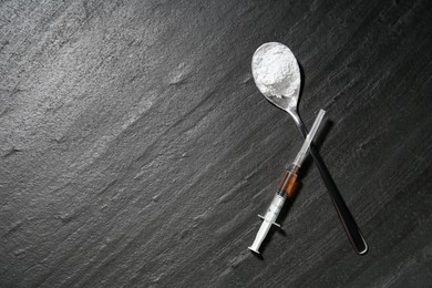 Photo of Drug addiction. Spoon with powder and syringe on dark textured table, flat lay. Space for text