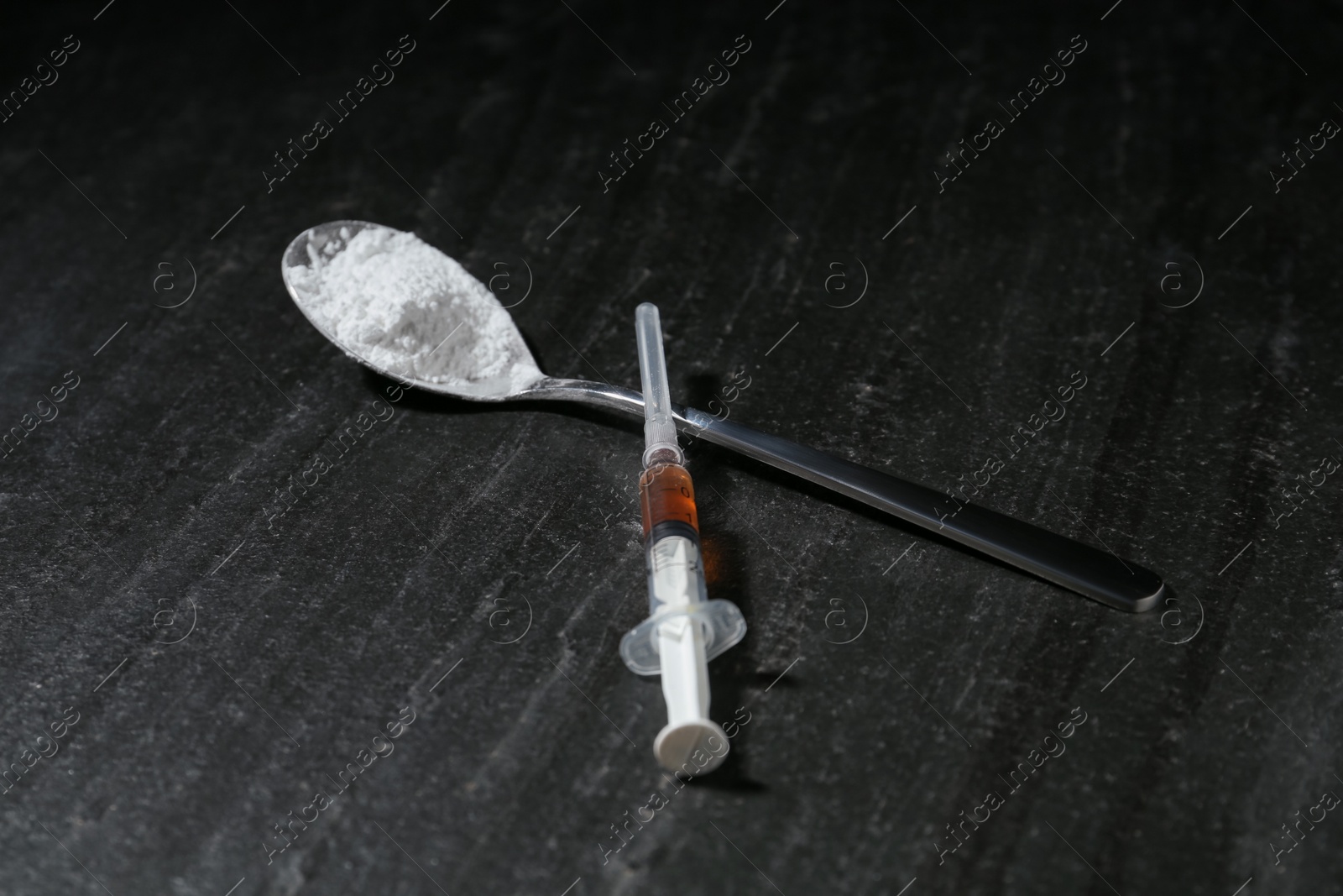 Photo of Drug addiction. Spoon with powder and syringe on dark textured table