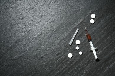 Photo of Drug addiction. Syringe and pills on dark textured table, flat lay. Space for text