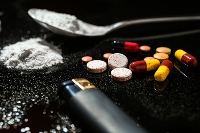 Photo of Drug addiction. Spoon with powder, pills and cigarette lighter on black table, closeup