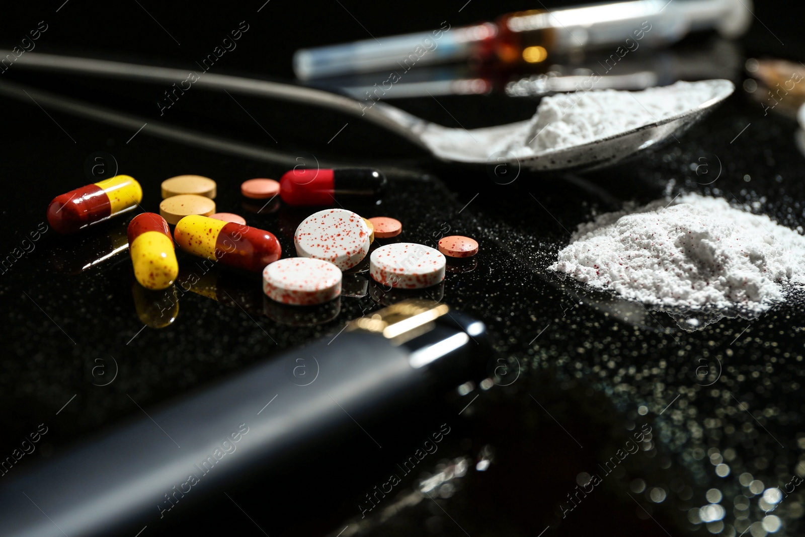 Photo of Drug addiction. Spoon with powder, pills and cigarette lighter on black table, closeup