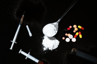 Photo of Drug addiction. Spoon with powder, pills and cigarette lighter on black table, flat lay