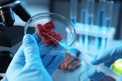 Photo of GMO concept. Scientist injecting something into piece of meat in laboratory, closeup