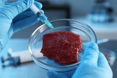 Photo of GMO concept. Scientist injecting something into piece of meat in laboratory, closeup